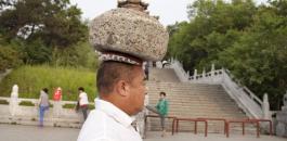 صيني يحمل حجراً ثقيلاً على رأسه ويسير به بشكل يومي بهدف خسارة وزنه الزائد