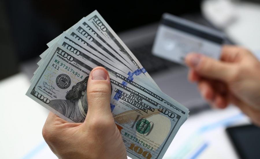 male-hand-holds-dollar-banknotes-and-plastic-bank-card-in-hands-closeup-cash-out-money-earned-on-web-to-your-account-cashes-through-payment-terminal-pay-per-click-concept-scaled.jpg