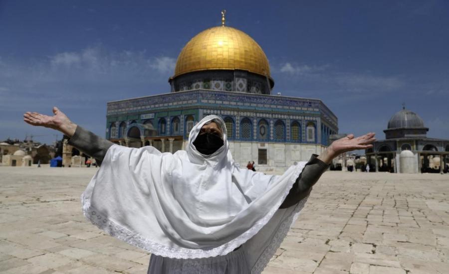 A Palestinian woman raises her arms in prayer as she takes part in the first Friday prayers of the Muslim fasting month of Ramadan at the Al-Aqsa Mosque compound, Islam's first Qibla, 16 April 2021 (AFP).jpg